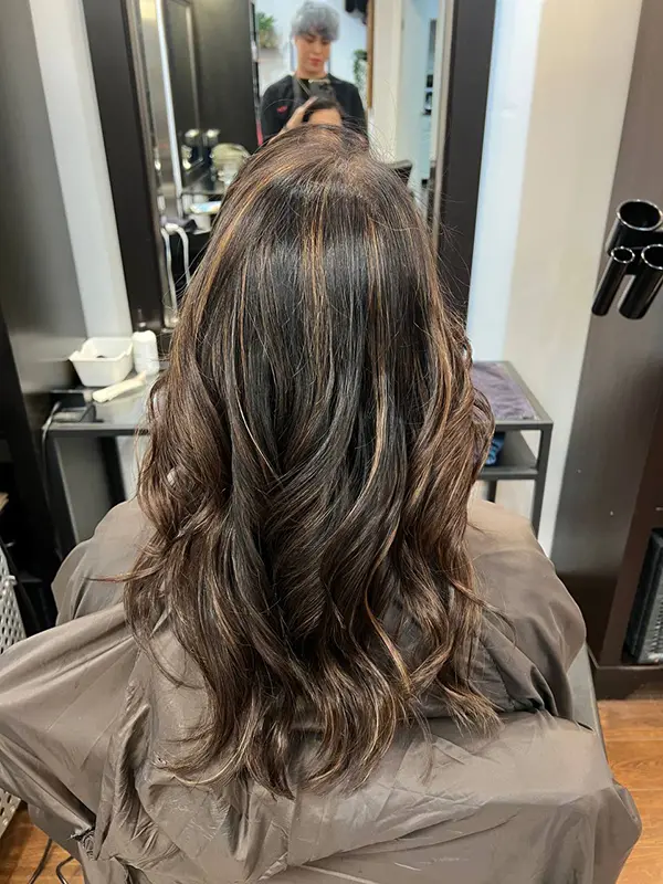 Soft brunette balayage with subtle face-framing highlights and loose waves by CocoRez in Port Coquitlam.
