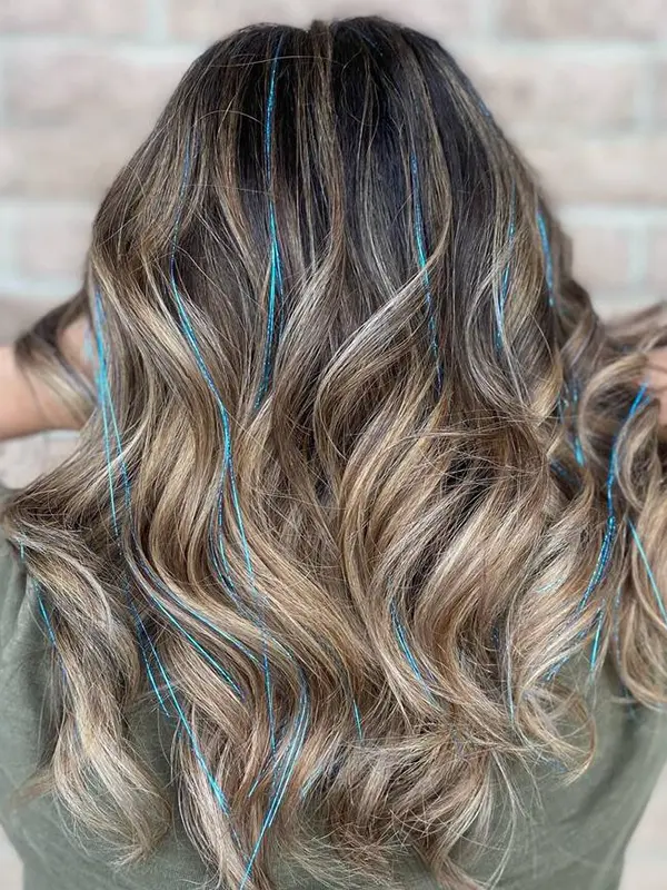 Blue hair tinsel professionally installed on highlighted wavy hair at CocoRez in Port Coquitlam.