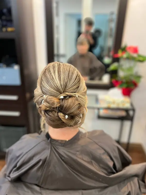 Elegant low updo hairstyle with soft twists and decorative pins by CocoRez in Port Coquitlam.