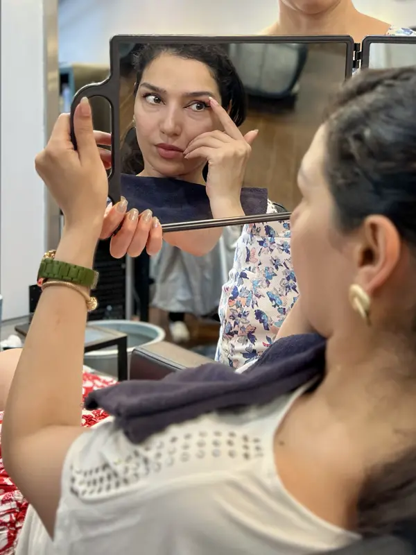 Client checking her newly shaped eyebrows after a professional eyebrow shaping service at CocoRez in Port Coquitlam.