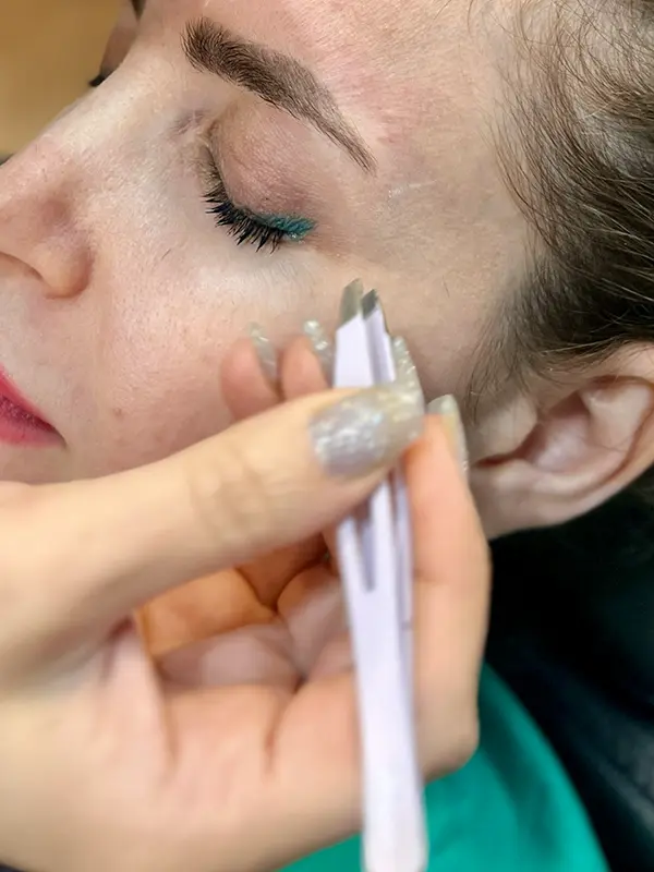 Precision eyebrow shaping with tweezers to refine natural brow definition at CocoRez in Port Coquitlam.
