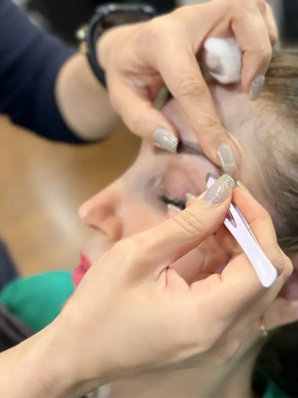 Professional eyebrow detailing with precision tweezers during an eyebrow threading service at CocoRez in Port Coquitlam.
